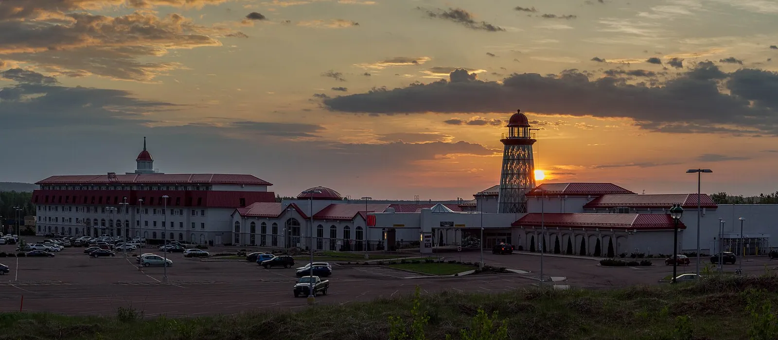 Casino New Brunswick in Moncton at sunset: the hotel block, red-roofed casino wings and lighthouse-style tower beyond the parking lot